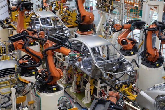 Brazos robóticos ensamblando carrocerías de autos en una planta de producción.