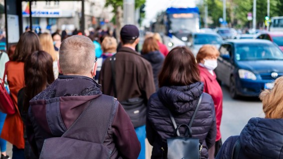 Grupo de personas esperando para cruzar la calle en una ciudad con tránsito activo.