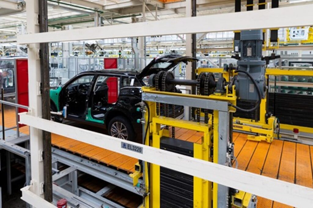 Automóvil en proceso de ensamblaje dentro de una línea de producción industrial, rodeado de maquinaria y equipos automatizados.