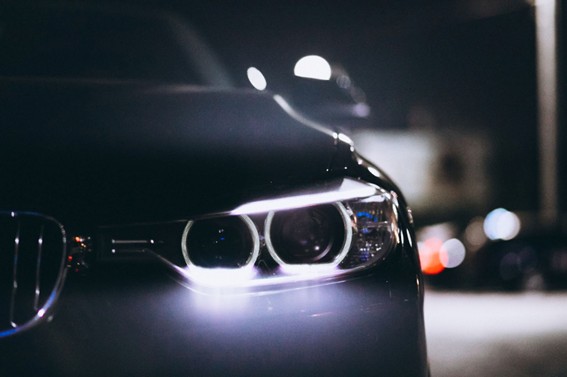 Vista cercana del frente de un automóvil con luces LED encendidas durante la noche, resaltando el detalle de los faros.